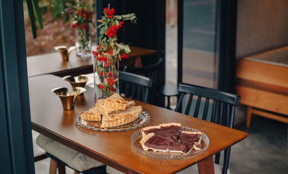 Table élégante avec des tartes, des bouchées et un vase de fleurs décoratif. Ambiance conviviale et raffinée.